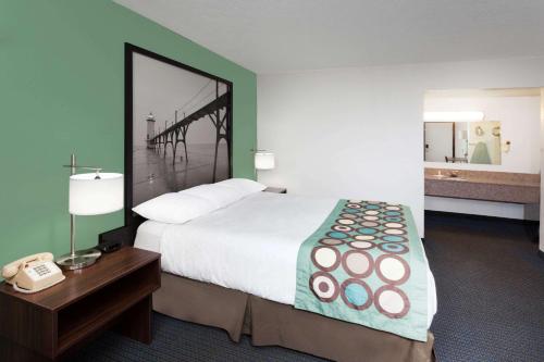 a hotel room with a large bed and a telephone at Super 8 by Wyndham Stevensville St Joseph in Stevensville