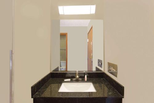 La salle de bains est pourvue d'un lavabo et d'un miroir. dans l'établissement Super 8 by Wyndham Normal Bloomington, à Bloomington