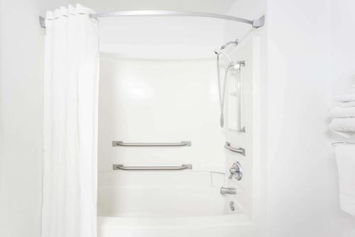 baño blanco con ducha y lavamanos en Super 8 by Wyndham Pontiac, en Pontiac
