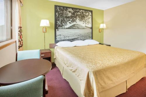 a hotel room with a bed and a table and chairs at Super 8 by Wyndham Normal Bloomington in Bloomington