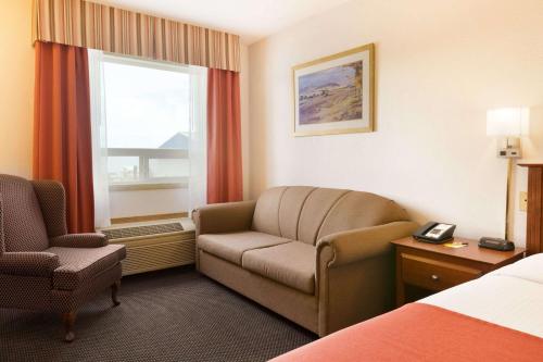 a hotel room with a couch and a window at Super 8 by Wyndham Drayton Valley in Drayton Valley