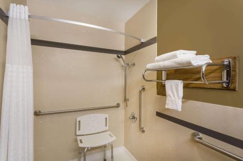 a bathroom with a shower and a toilet and a chair at Super 8 by Wyndham Martinez in Martinez