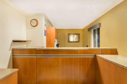a kitchen with wooden cabinets and a clock on the wall at Super 8 by Wyndham Martinez in Martinez