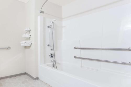 a white bathroom with a shower and a tub at Super 8 by Wyndham Moose Jaw SK in Moose Jaw