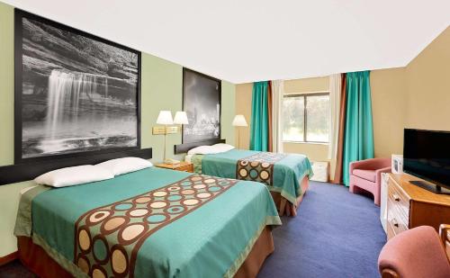 a hotel room with two beds and a flat screen tv at Super 8 by Wyndham Macomb in Macomb