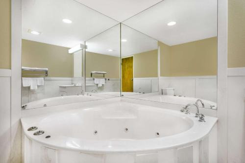 a large white tub in a bathroom with a large mirror at Super 8 by Wyndham Bentonville in Bentonville