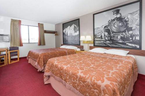 a hotel room with two beds and a train on the wall at Super 8 by Wyndham Grand Junction Colorado in Grand Junction