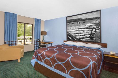 a hotel room with a bed and a large picture on the wall at Super 8 by Wyndham Bentonville in Bentonville