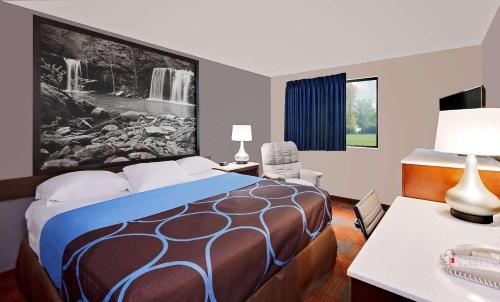 a hotel room with a bed and a desk with a phone at Super 8 by Wyndham Fayetteville in Fayetteville