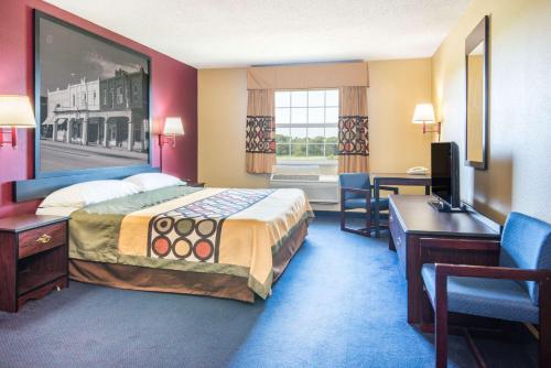a hotel room with a bed and a desk and a computer at Super 8 by Wyndham Big Cabin/Vinita Area in Vinita