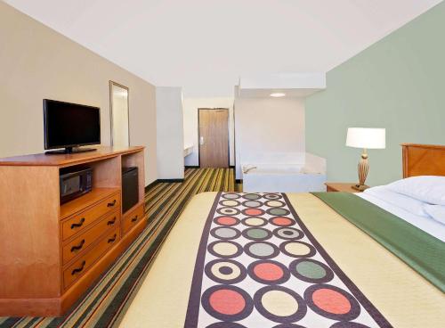 a hotel room with a bed and a flat screen tv at Super 8 by Wyndham Mt. Pleasant in Mount Pleasant