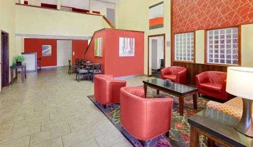 a waiting room with red chairs and tables at Super 8 by Wyndham Mt. Pleasant in Mount Pleasant