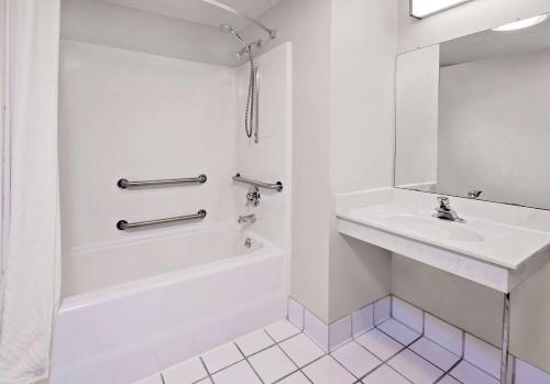 a white bathroom with a tub and a sink at Super 8 by Wyndham Mt. Pleasant in Mount Pleasant
