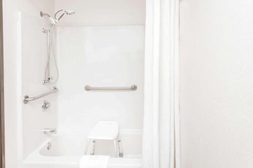 baño blanco con ducha y aseo blanco en Super 8 by Wyndham Lincoln, en Lincoln