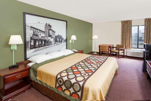 a hotel room with a large bed with a picture on the wall at Super 8 by Wyndham Lincoln in Lincoln