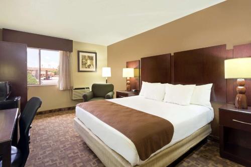 ein Hotelzimmer mit einem großen Bett und einem Schreibtisch in der Unterkunft Super 8 by Wyndham Chandler Phoenix in Chandler
