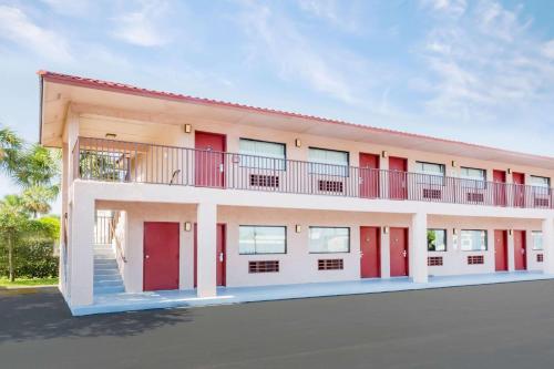 a building with red doors and a balcony at Redfinn Inn in Fort Pierce