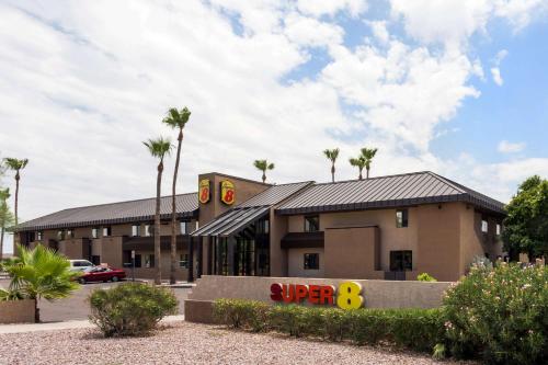 a building with palm trees in a parking lot at Super 8 by Wyndham Chandler Phoenix in Chandler