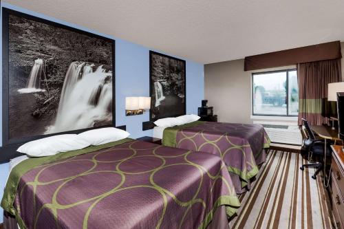 a hotel room with two beds and a tv at Super 8 by Wyndham Jonesboro in Jonesboro