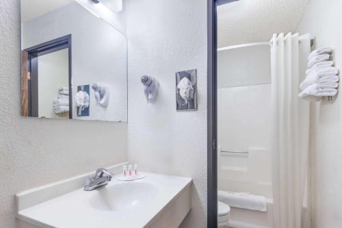 Baño blanco con lavabo y espejo en Super 8 by Wyndham Lake Havasu City en Lake Havasu City