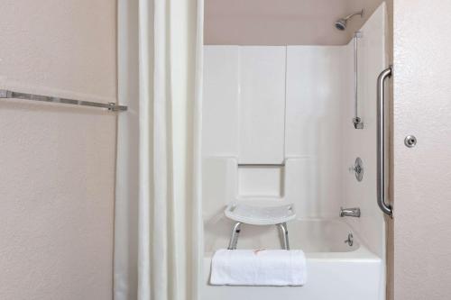 a bathroom with a shower with a stool next to a tub at Super 8 by Wyndham Lake Havasu City in Lake Havasu City