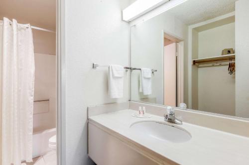 Baño blanco con lavabo y espejo en Super 8 by Wyndham Bakersfield/Central en Bakersfield