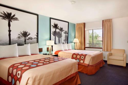 a hotel room with two beds and a chair at Super 8 by Wyndham Indio in Indio