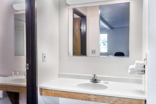 Super 8 by Wyndham Delmont في Delmont: حمام أبيض مع حوض ومرآة
