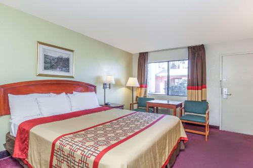 a hotel room with a bed and a chair and a window at Super 8 by Wyndham Bakersfield/Central in Bakersfield