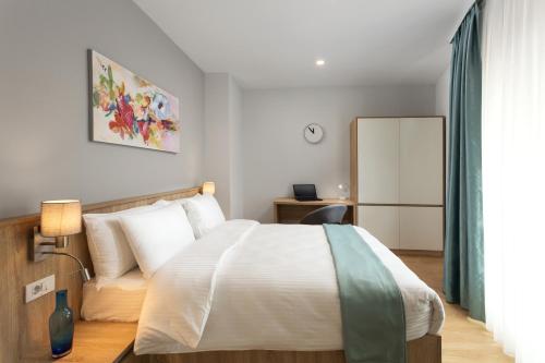 a bedroom with a white bed and a couch at Athina Suites Hotel in Bucharest