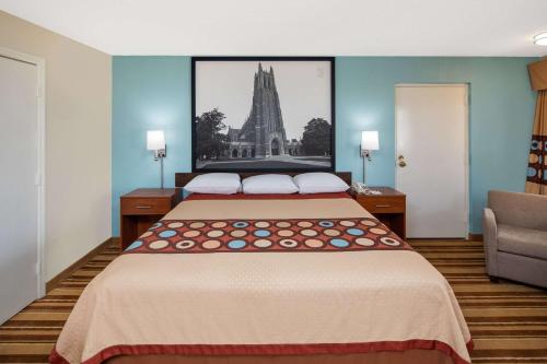a bedroom with a large bed with a picture on the wall at Super 8 by Wyndham Burlington NC in Burlington