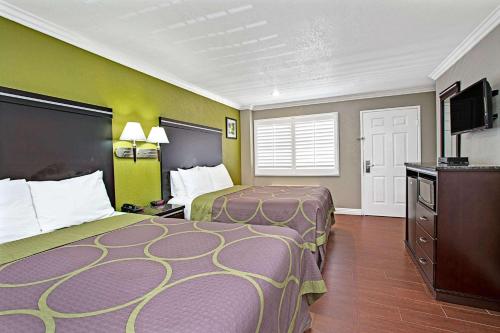 a hotel room with two beds and a flat screen tv at Super 8 by Wyndham Inglewood/LAX/LA Airport in Inglewood