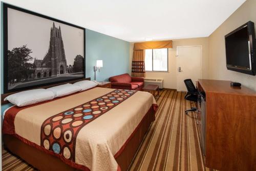 a hotel room with a large bed and a tv at Super 8 by Wyndham Burlington NC in Burlington