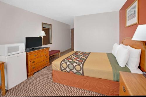 a hotel room with a bed and a flat screen tv at Super 8 by Wyndham Crystal Lake in Crystal Lake