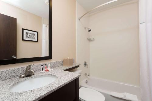 a bathroom with a sink and a toilet and a mirror at Super 8 by Wyndham Longmont/Twin Peaks in Longmont