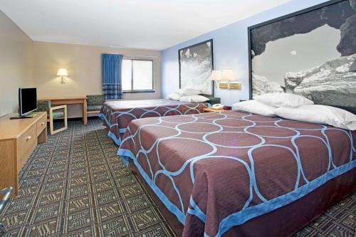 a hotel room with two beds and a flat screen tv at Super 8 by Wyndham Fort Collins in Fort Collins