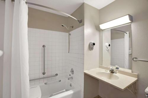 y baño blanco con lavabo y ducha. en Super 8 by Wyndham Crystal Lake, en Crystal Lake