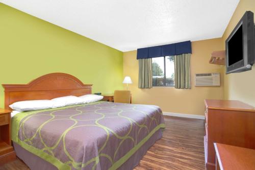a hotel room with a bed and a flat screen tv at Super-8-Gainesville-I-75-Hospital-University-Area in Gainesville