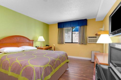 a hotel room with a bed and a flat screen tv at Super-8-Gainesville-I-75-Hospital-University-Area in Gainesville
