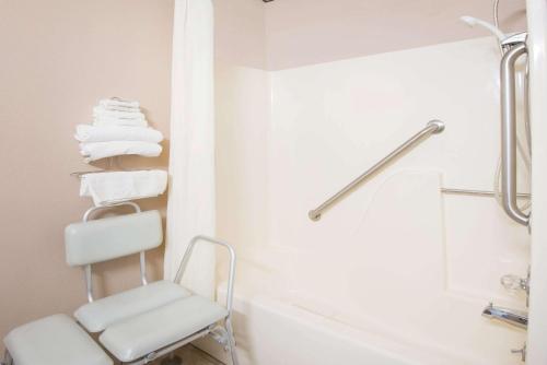 a white bathroom with a towel rack and a chair at Super 8 by Wyndham Abilene KS in Abilene