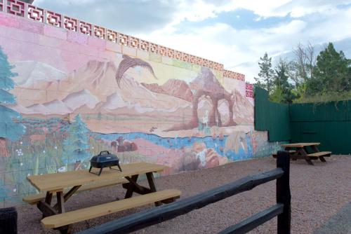 a wall with a mural on it with two picnic tables at Super 8 by Wyndham Cortez/Mesa Verde Area in Cortez