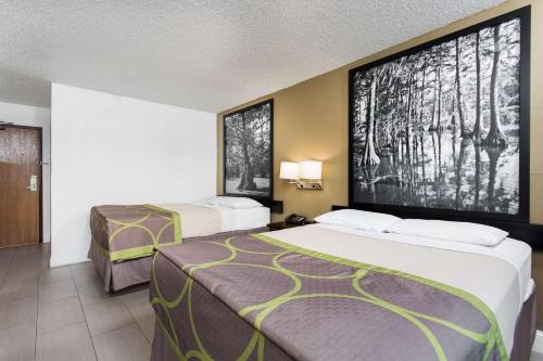 a hotel room with two beds and a large screen at Super 8 by Wyndham Greensboro/Coliseum/Conv. in Greensboro