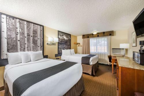 a hotel room with two beds and a desk at Super 8 by Wyndham Canon City in Canon City