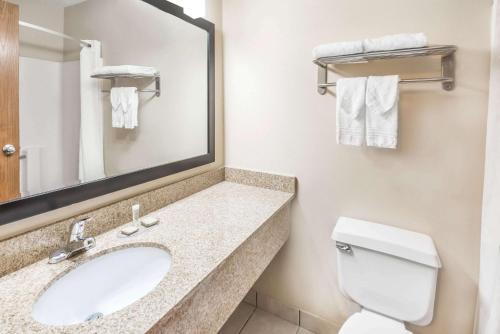 Super 8 by Wyndham Bloomington University Area في بلومنغتون: حمام مع حوض ومرحاض ومرآة
