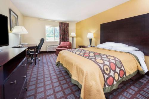 a hotel room with a large bed and a desk at Super 8 by Wyndham Bloomington University Area in Bloomington
