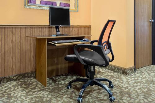 a desk with a computer monitor and a chair at Super 8 by Wyndham Antigo in Antigo