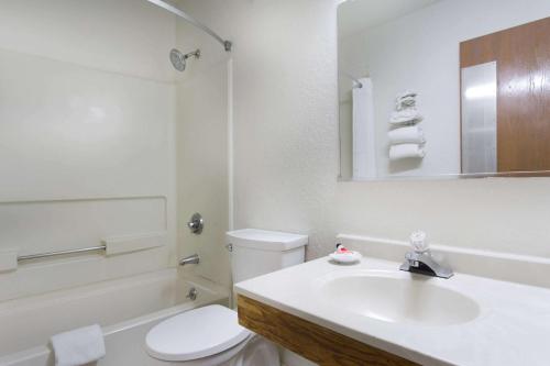 Baño blanco con aseo y lavamanos en Super 8 by Wyndham Greensboro/Coliseum/Conv., en Greensboro