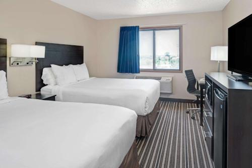 a hotel room with two beds and a flat screen tv at Super 8 by Wyndham Omaha I-80 West in Omaha