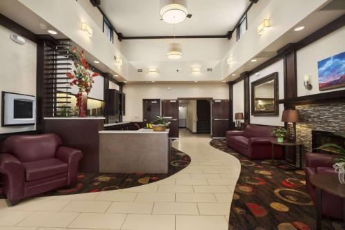 a lobby of a hotel with purple chairs and a fireplace at Super 8 by Wyndham Conrad in Conrad