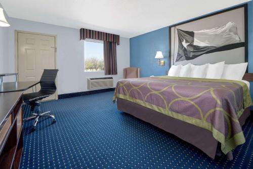 a hotel room with a large bed and a desk at Super 8 by Wyndham Dumas TX in Dumas